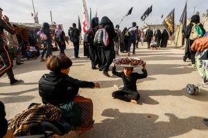 دختر عراقی که سینی خرما را بر سر گرفته تا از زوار اربعین پذیرایی کند