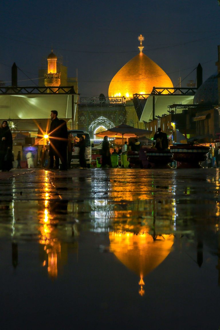 بازتاب گنبد طلایی حرم در سطح خیس خیابان