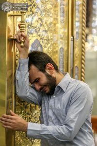 زائری که به در ورودی روضه منوره متوسل شده است