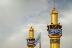 گلدسته‌های حرم و پرچم غدیر در میان آن‌ها