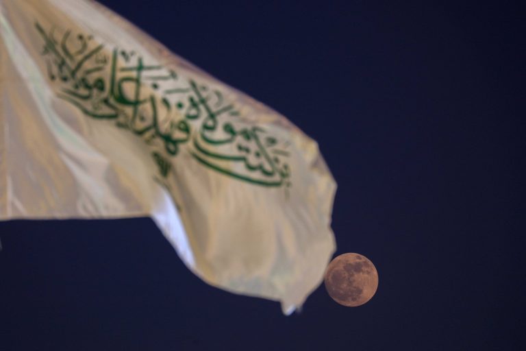 پرچم من کنت مولاه همراه با ماه کامل در آسمان شب