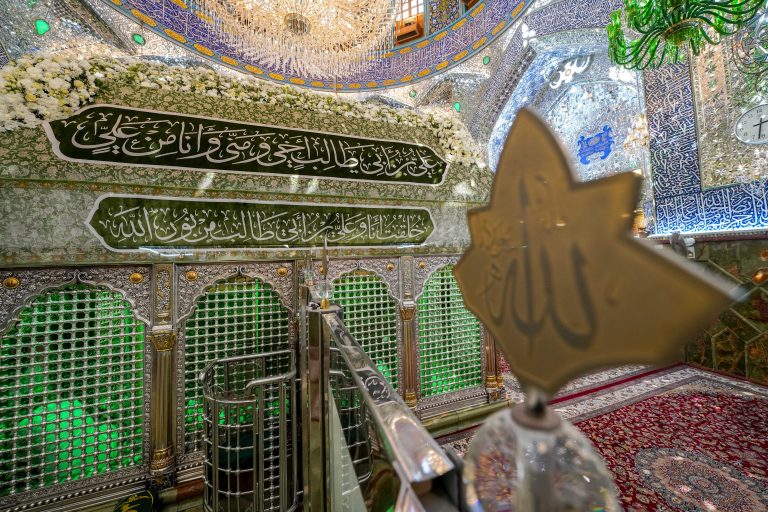 نقش الله و حائل میان دو قسمت مضجع و ضریح شریف امیرالمؤمنین با گل‌آرایی به مناسبت میلاد سمت چپ