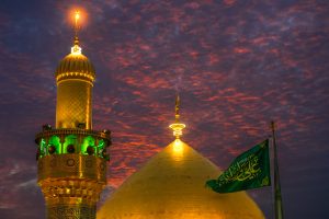 گنبد گلدسته پرچم سبز علی ولی الله و آسمان پوشیده از ابر نارنجی و کبود