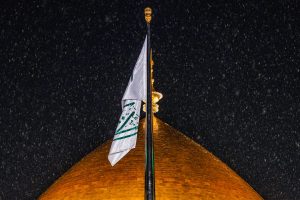 پرچم و گنبد طلایی حرم امام علی و بارش باران