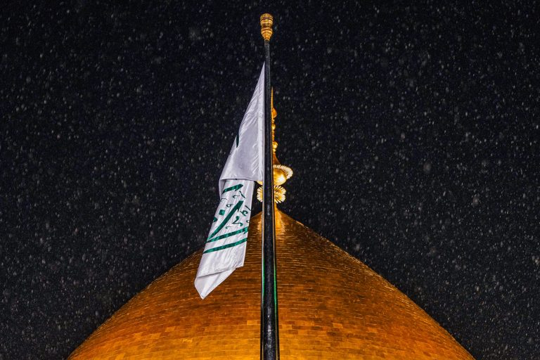 پرچم و گنبد طلایی حرم امام علی و بارش باران