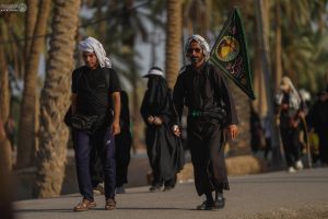 دو مرد در حال پیاده‌روی به سمت کربلا از مسیر نخلستان