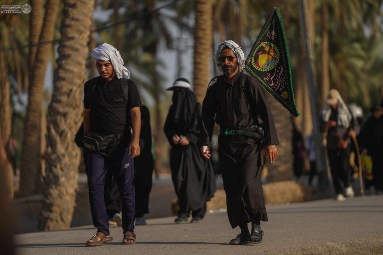 دو مرد در حال پیاده‌روی به سمت کربلا از مسیر نخلستان