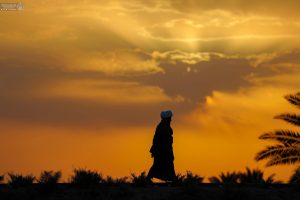 یک روحانی در مسیر پیاده‌روی اربعین با نور غروب