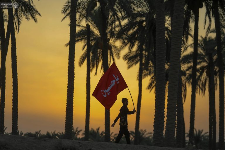 یک زائر جوان با پرچم یا حسین در پیاده‌روی اربعین