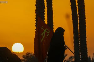 خانم زائر اربعینی با پرچم یا حسین و غروب آفتاب