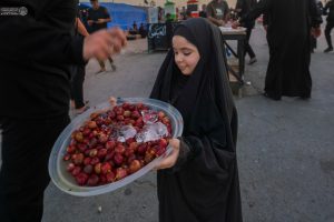 دختری در حال تعارف میوه، پیاده‌روی اربعین