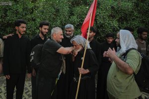 خادم حسینی در حال بوسیدن دست زائر