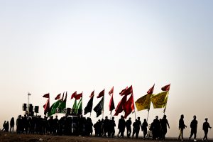زائران اربعین با پرچم‌های رنگی در افق