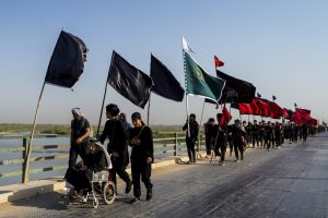 چندین نفر از زائران پیاده در حال عبور از پل