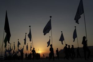سایه زائران پیاده اربعینی با پرچم در طلوع آفتاب