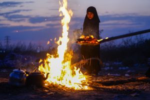 دختری کنار آتش و چای در مسیر اربعین