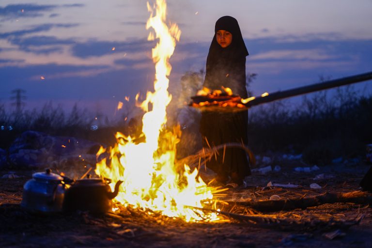 دختری کنار آتش و چای در مسیر اربعین