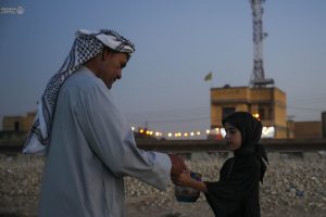 دختربچه و مردی در حال آماده کردن آب خنک برای زوار پیاده