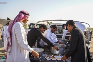 خادمان موکب از کنار خودرو در حال توزیع غذا هستند.