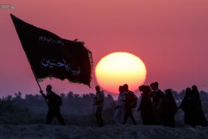 سیلوئت زائران پیاده اربعین و پرچم مشکی در غروب