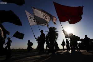 سیلوئت زائران و چند پرچم در برابر خورشید