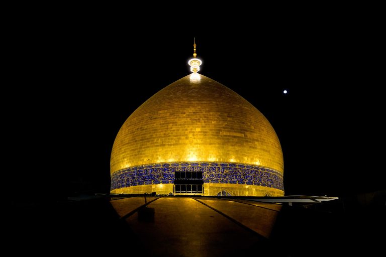 گنبد حرم امیرالمؤمنین با نورپردازی شبانه در قاب تاریک