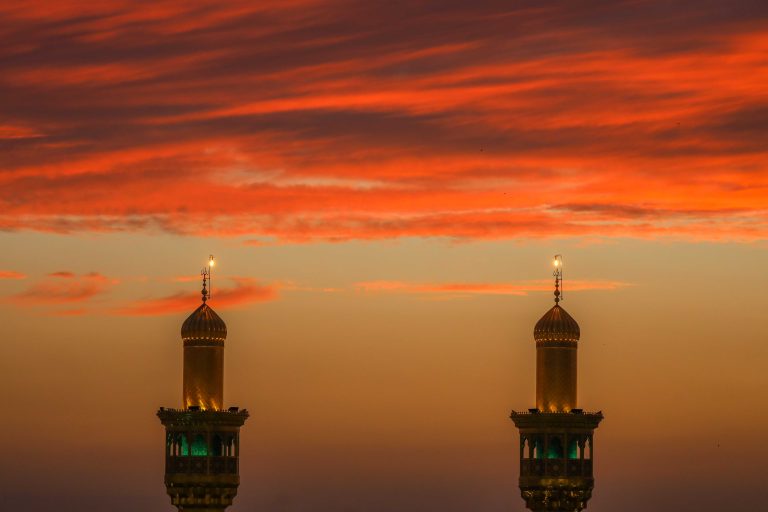 دو مناره طلایی حرم علوی در برابر آسمان سرخ غروب