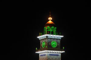 مناره ساعت حرم علوی با نور سبز در شب
