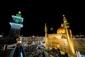 نمای شبانه حرم مطهر با گنبد طلایی و مناره ساعت