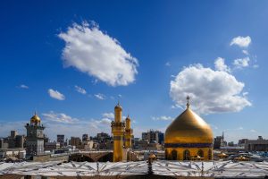 نمای روز حرم علوی با گنبد طلایی و گلدسته‌ها در میان آسمان آبی