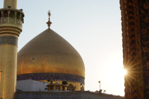 نمایی از گنبد طلایی حرم مطهر امیرالمؤمنین علی (علیه‌السلام) در برابر نور خورشید که از کنار بنای حرم می‌تابد