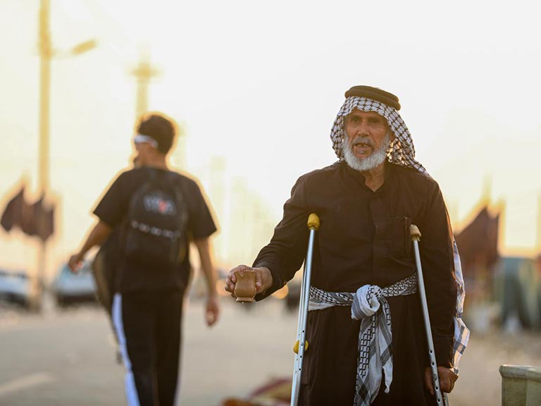 پیرمرد کم‌توانی که در مسیر پیاده‌روی اربعین خدمت می‌کند