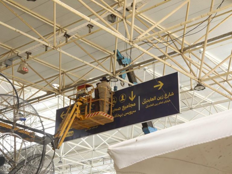 خادمان آستان مقدس علوی در حال نصب تابلوهای راهنما برای آماده‌سازی ایام زیارت اربعین