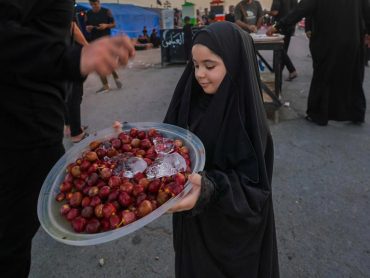 دختر عراقی در حال تقدیم میوه به زوار اربعین